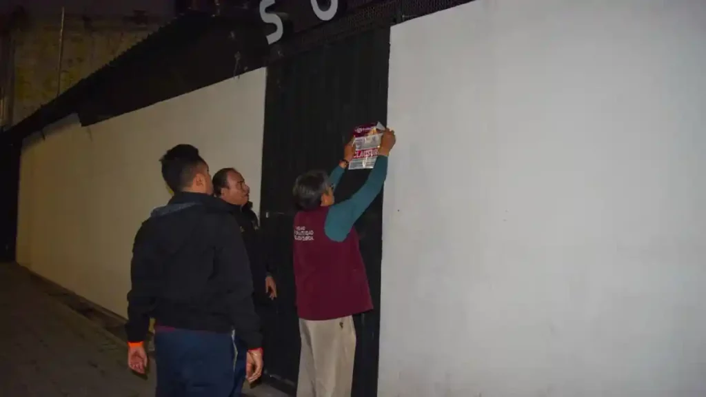 Trabajadores de la Unidad de Normatividad y Regulación Comercial colocando el sello de clausura en el bar.